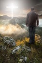 Man on top of the mountain looking at the Christian Cross Royalty Free Stock Photo