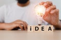 Man touch Light bulb on wooden cube blocks with word IDEA. creative genius innovation technology knowledge successful. symbol Royalty Free Stock Photo