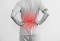 A man touching his back, with red highlight. Back pain, backache and waist pain