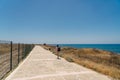 Man tourist with backpack walk along walking path at rocky coast of Mediterranean Sea in city Paphos of Cyprus in summer Royalty Free Stock Photo