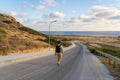 Man tourist with backpack walks down mountain along asphalt road towards mediterranean sea in cyprus in area of Agios Royalty Free Stock Photo