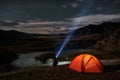 Man tourist with flashlight near his camp tent at night. Royalty Free Stock Photo