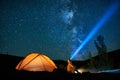 Man tourist with flashlight near his camp tent at night. Royalty Free Stock Photo