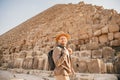 Man tourist with hat and bag walks background of pyramids in Giza Cairo Egypt, sun light travel Royalty Free Stock Photo