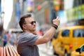 Man tourist shooting or taking selfie on Times Square on sunny summer day, downtown Manhattan, New York Royalty Free Stock Photo