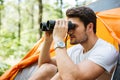 Man tourist sitting and looking at binoculars in forest Royalty Free Stock Photo