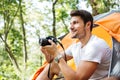Man tourist sitting and using modern photo camera in forest Royalty Free Stock Photo