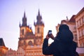 Man / tourist taking photos of a monument with mobile phone. Prague .Young man with backpack, taking pictures of street on smart p