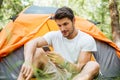 Man tourist using mobile phone in toristic tent at forest Royalty Free Stock Photo