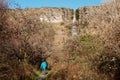 Man tourist walking on a foot path in a forest. Devil`s chimney waterfall in the background. Warm sunny day. Travel and nature