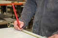 A man traces measurements on a PVC door frame in a carpentry.