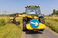 Man in a tractor using a flail to cut grass verges in a country lane. UK