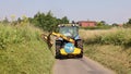 Man in a tractor using a flail to cut grass verges in a country lane. UK