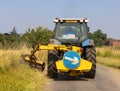 Man in a tractor using a flail to cut grass verges in a country lane. UK Royalty Free Stock Photo