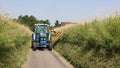 Man in a tractor using a flail to cut grass verges in a country lane. UK