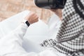 A man in traditional Arabic clothes thobe looks at his wristwatch.