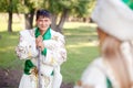 Man in traditional festive dress of steppe nomads, leaned on his cane, looking at wife.