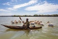 Man on a traditional and primitive bamboo boat feeding pelicans on Lake Tana