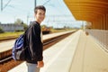 Man on train station, travel. Student in railway station. Smile freelance man. Boy with backpack waiting in a train station in sun Royalty Free Stock Photo