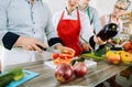 Man in training kitchen cutting vegetables under watchful eye of dietician Royalty Free Stock Photo