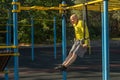 Man trains with gymnastic rings on a street sports ground on a sunny day.