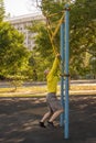 Man trains on a rock climbing machine on a street sports ground.