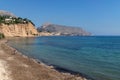 Man at tranquil stone beach along ocean with view on rocky cliffs, Altea, Costa Blanca, Spain Royalty Free Stock Photo