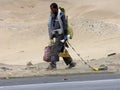 Punta Negra, Peru, 05-09-2005 maintenance worker walking along panamerican highway with bags of trash