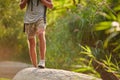 Male legs hiking at mountain peak. Trekking shoes on hiker feet outdoors crossing rock stones on river creek. Royalty Free Stock Photo