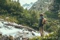 Man traveler alone with backpack looking at mountain river among green woods Royalty Free Stock Photo