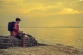 Man traveler with backpack on the rocks near the sea at sunset a Royalty Free Stock Photo