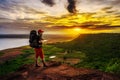 Man traveler with backpack standing on edge of cliff, on a top of the rock mountain at sunset Royalty Free Stock Photo