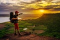 Man traveler with backpack standing on edge of cliff, on a top of the rock mountain at sunset Royalty Free Stock Photo