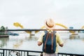 Man Traveler with backpack visiting in Da Nang. Tourist sightseeing the river view with Dragon bridge at love lock bridge.