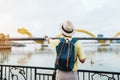 Man Traveler with backpack visiting in Da Nang. Tourist sightseeing the river view with Dragon bridge at love lock bridge.