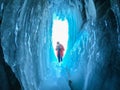 man traveler in orange jacket with camera in icicle frozen cave foreground