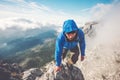 Man Traveler climbing on mountain summit over clouds