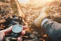 Man traveler hold compass in hand on background legs in hiking boots. Blurred background