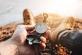 Man traveler hold compass in hand on background legs in hiking boots. Blurred background