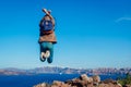 Man traveler jumping feeling free and happy on Santorini island in autumn. Tourist admiring Caldera view landscape