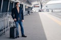 Man traveler poses with suitcase on wheels wears protective mask during pandemic outbreak afraids of dangerous influenza