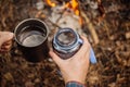 Man traveler pours water from a bottle into a metal mug.