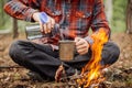 Man traveler pours water from a bottle into a metal mug.