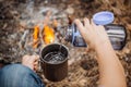 Man traveler pours water from a bottle into a metal mug. Royalty Free Stock Photo