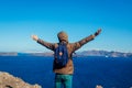 Man traveler raised arms feeling free and happy on Santorini island in autumn. Tourist admiring Caldera view landscape