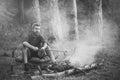 Man traveler roast sausages on stick on campfire in forest Royalty Free Stock Photo