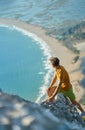 Man traveler on rock enjoying view on mountain over beautiful seashore valley Royalty Free Stock Photo