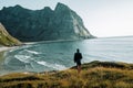 Man traveler on rocky enjoying beautiful mountain view and beach.