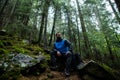 A man-traveler sits on a stone in the forest, a hot drink is being prepared