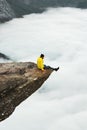 Man traveler sitting on Trolltunga rocky cliff edge